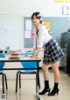 A woman in a school uniform standing next to a desk.