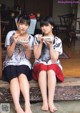 Two young women sitting on a bench eating food.