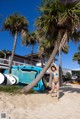 A woman in a blue bikini standing next to a palm tree.