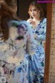 A woman in a blue floral dress looking at herself in the mirror.