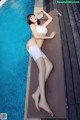 A woman in a white bikini laying on the edge of a pool.