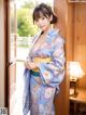 A woman in a blue kimono standing in front of a door.