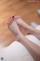 A woman's feet with red nail polish on a bed.