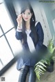 A woman in a school uniform sitting on a window sill.