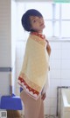 A woman standing in a bathroom holding a towel over her head.