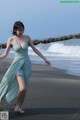 A woman in a blue dress walking on the beach.