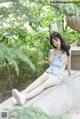 A woman sitting on a stone wall in a park.