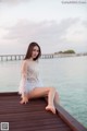 A woman sitting on a wooden dock by the water.