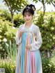 A woman in a blue and pink hanbok standing in a garden.